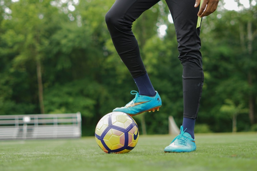 Player with a football on a grass pitch